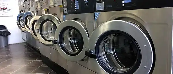 A row of JLA Smart 16 commercial washers receding down the launderette.