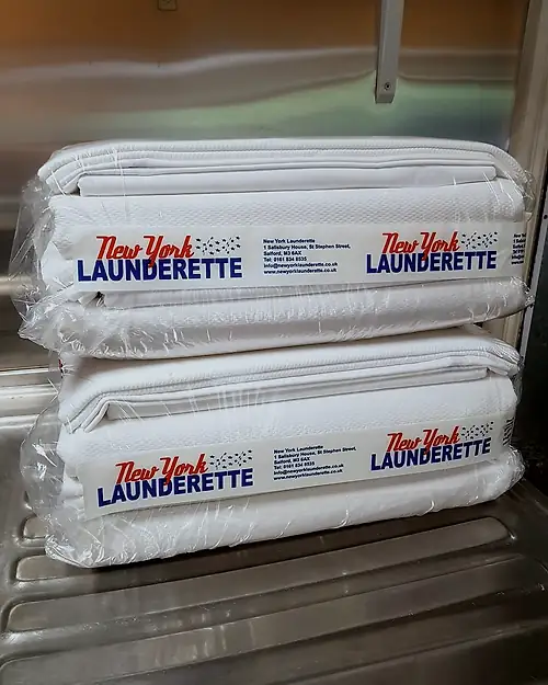 Two finished service washes folded, wrapped and sealed with red-and-blue New York Launderette bands.