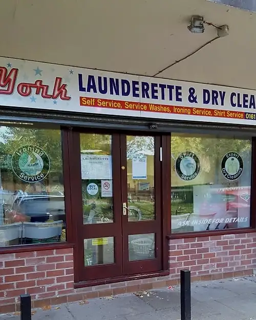 The red-brick shopfront, its fascia and window lettering listing self service, service washes, ironing service and shirt service.